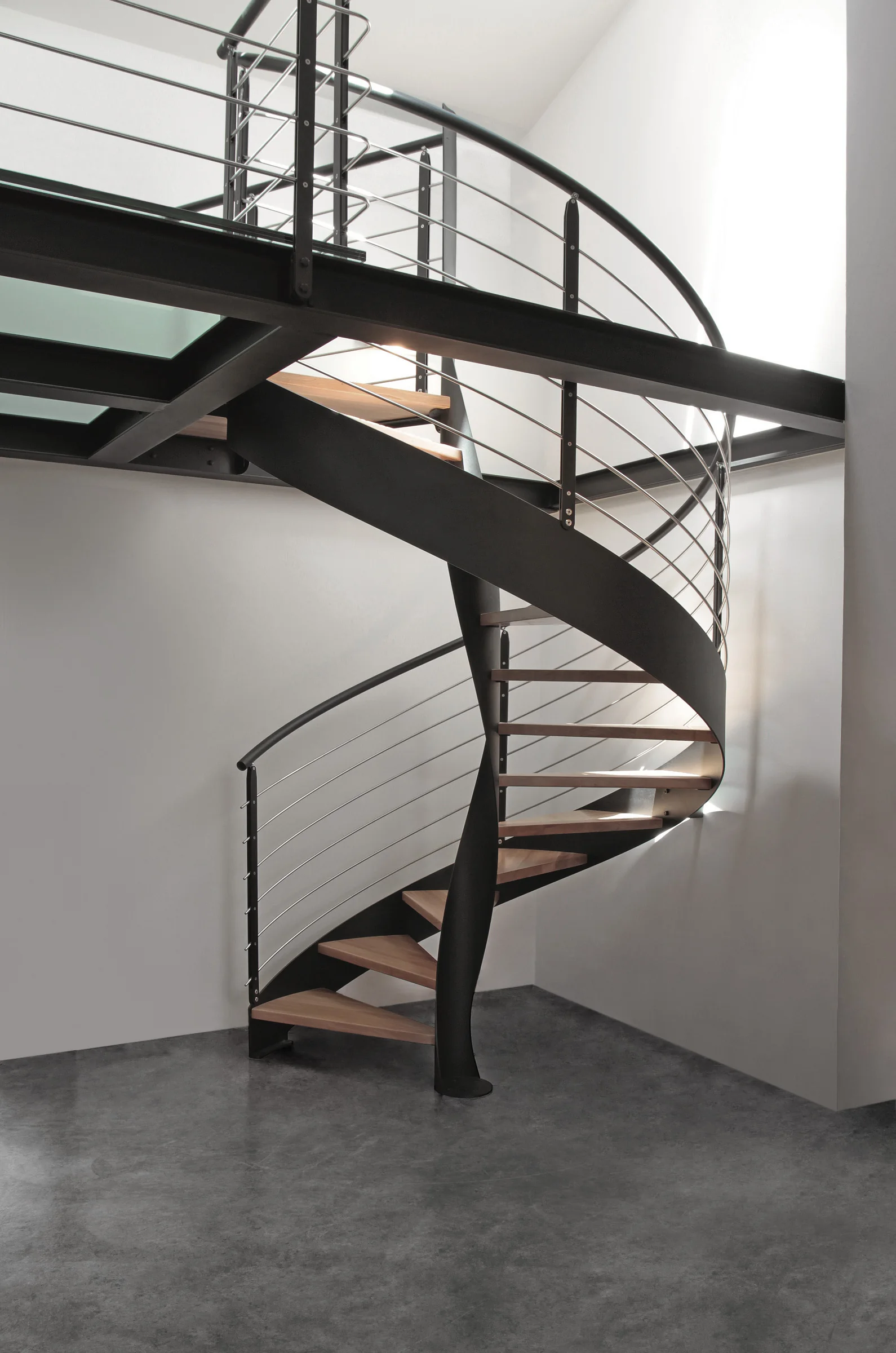 Spindeltreppe mit dunkler Metallwange, Holzstufen und filigranem Geländer
